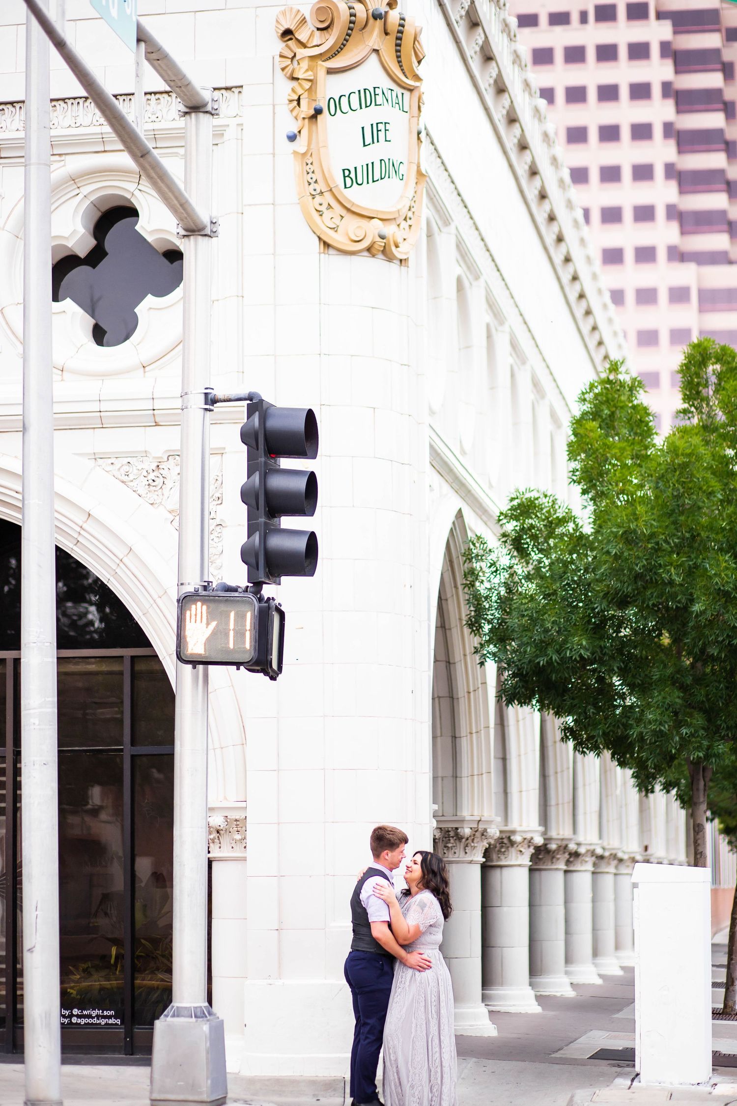 Elegant couple sharing intimate moment under white architectural columns in urban setting.