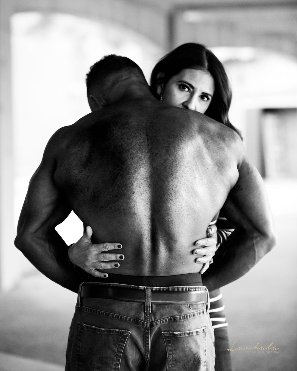 Intimate black and white portrait of couple embracing in natural light.