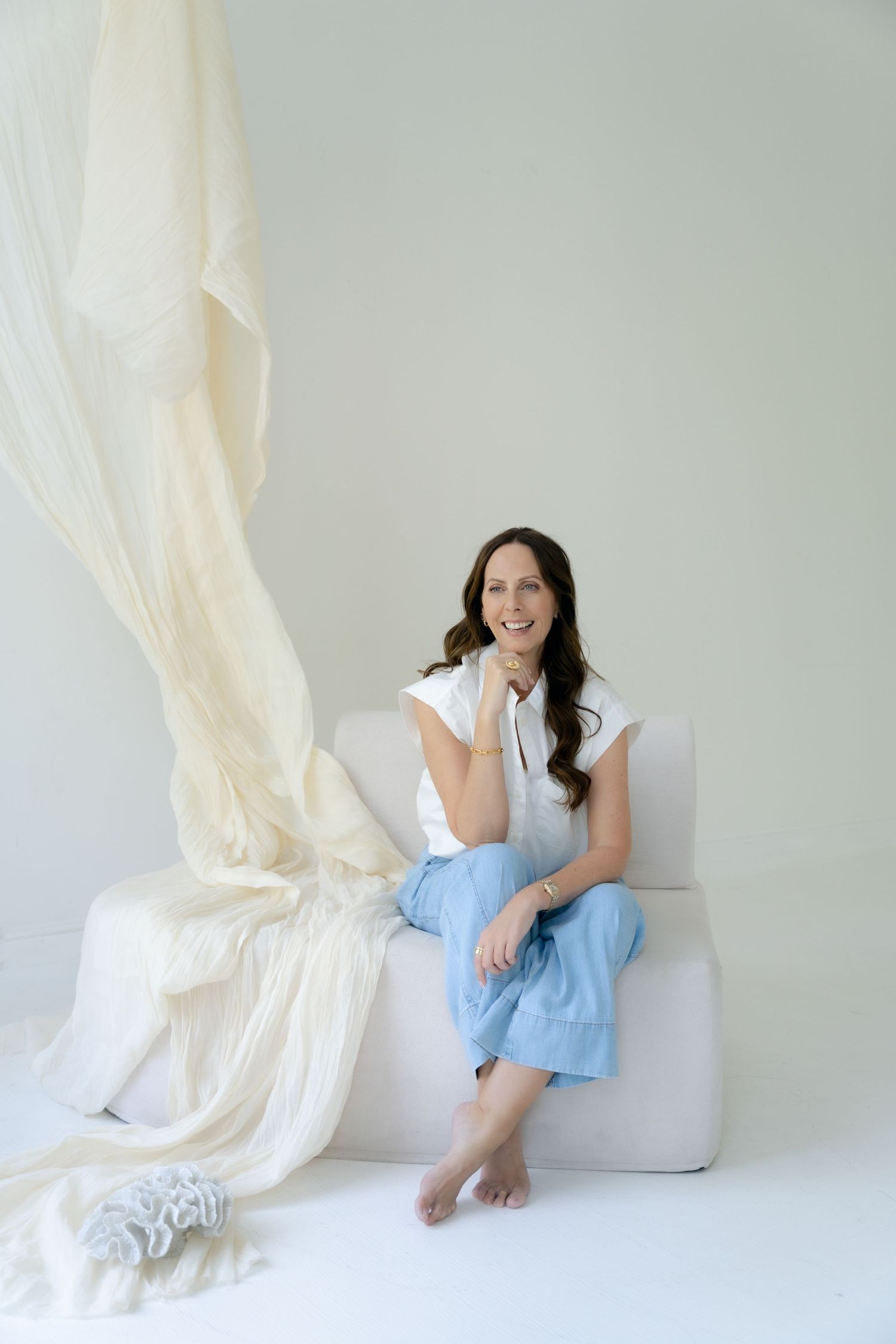 Person sitting on white couch in minimalist white room setting.
