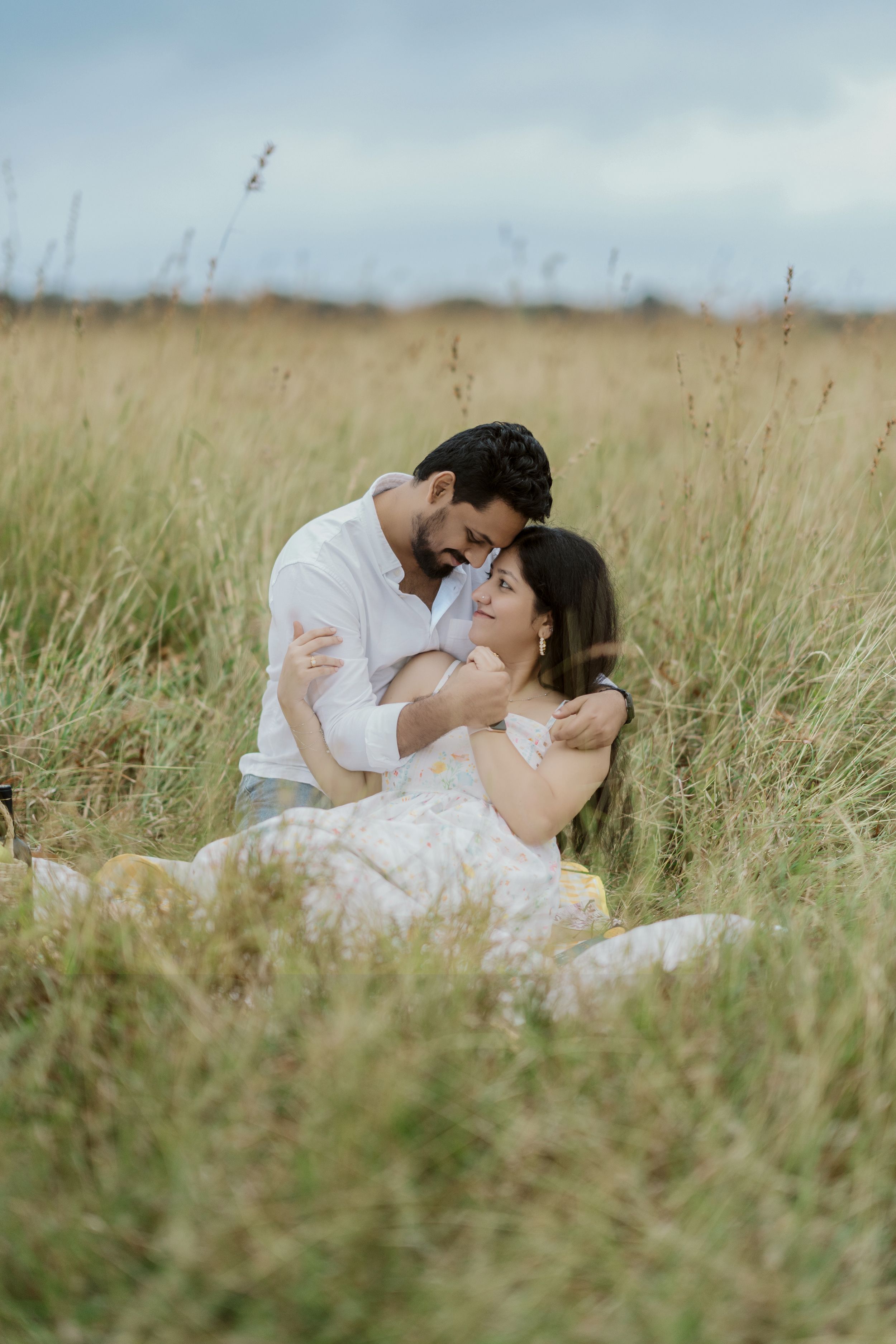 A couple in traditional Indian wedding attire pose beneath palm fronds.