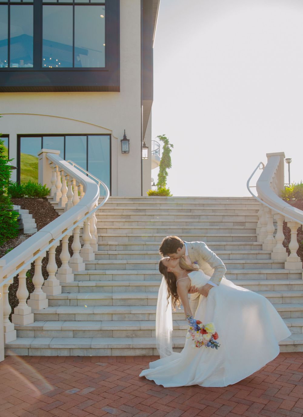 A graceful dip pose on elegant stone steps with ornate balustrades at a grand venue.
