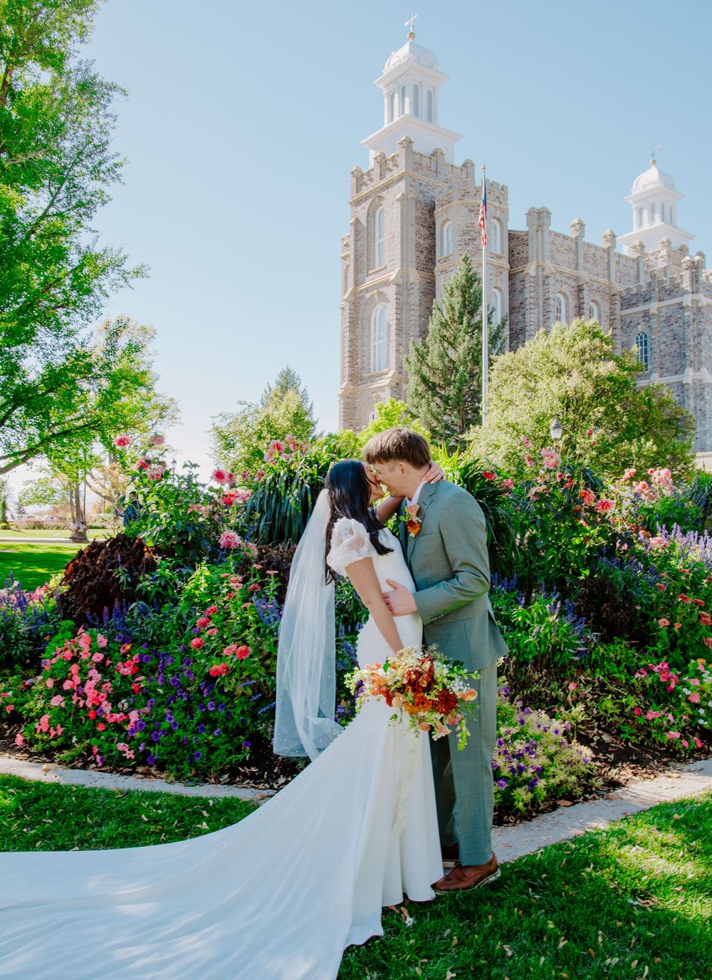 Wedding ceremony in front of Logan, Utah temple surrounded by vibrant rose gardens.