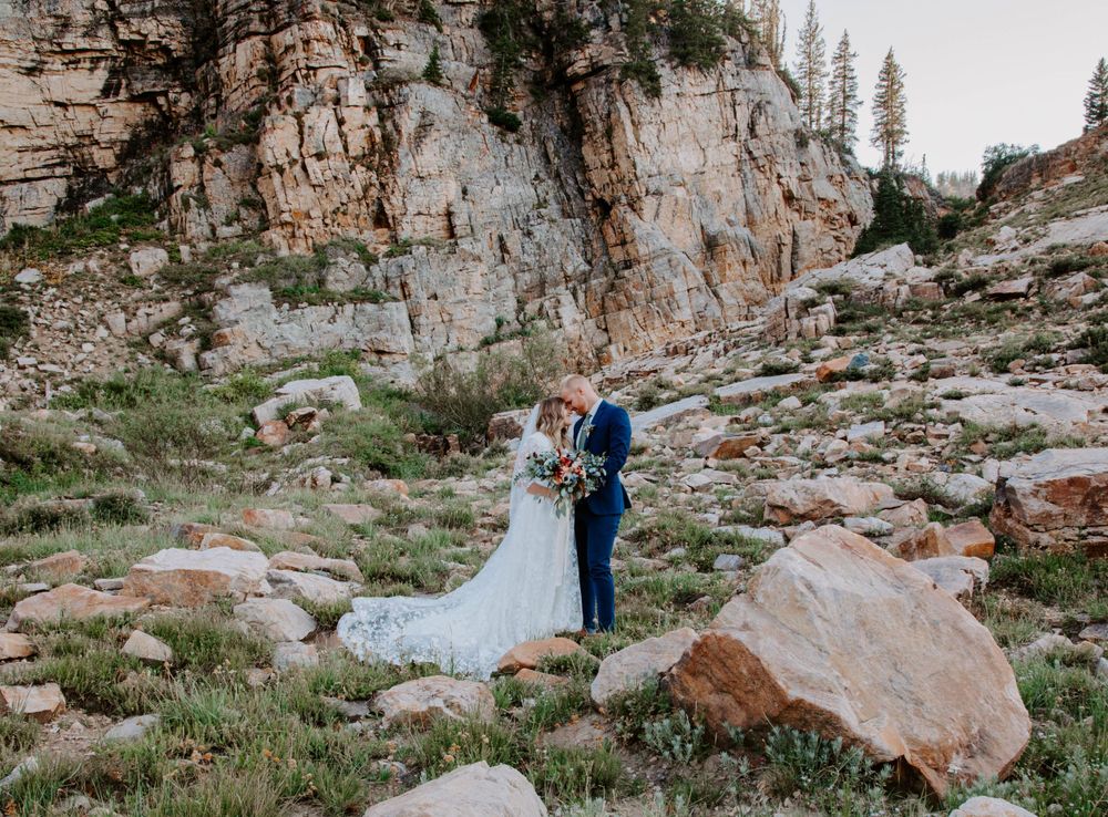 Scenic mountain engagement photoshoot with dramatic cliffs and natural rock formations in the background.