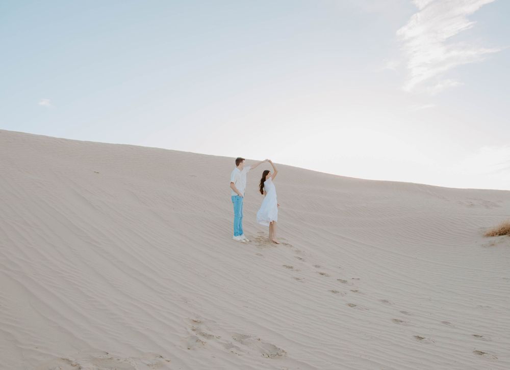 Minimalist white sand dunes stretching to the horizon under a bright blue sky.