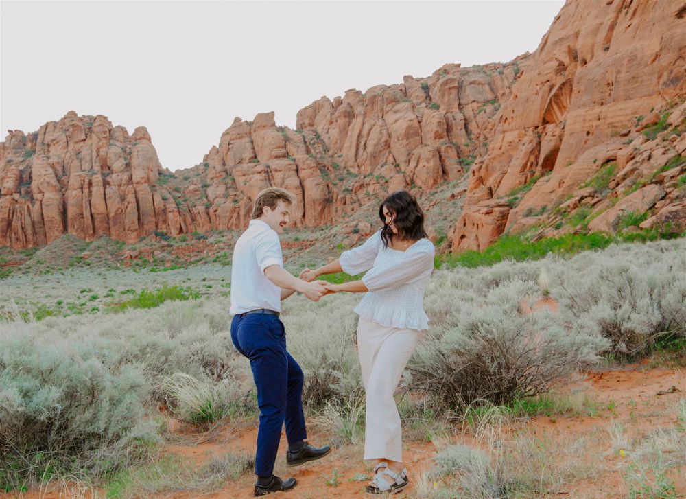A couple dances together on red rocks with towering canyon walls in the background.