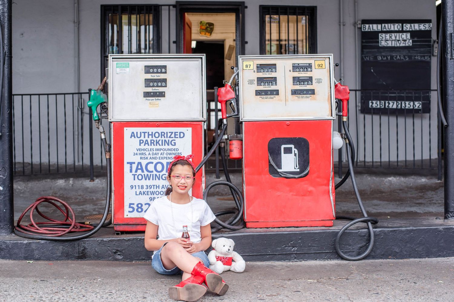 Gas station exterior with red and gray fuel pumps and signage.