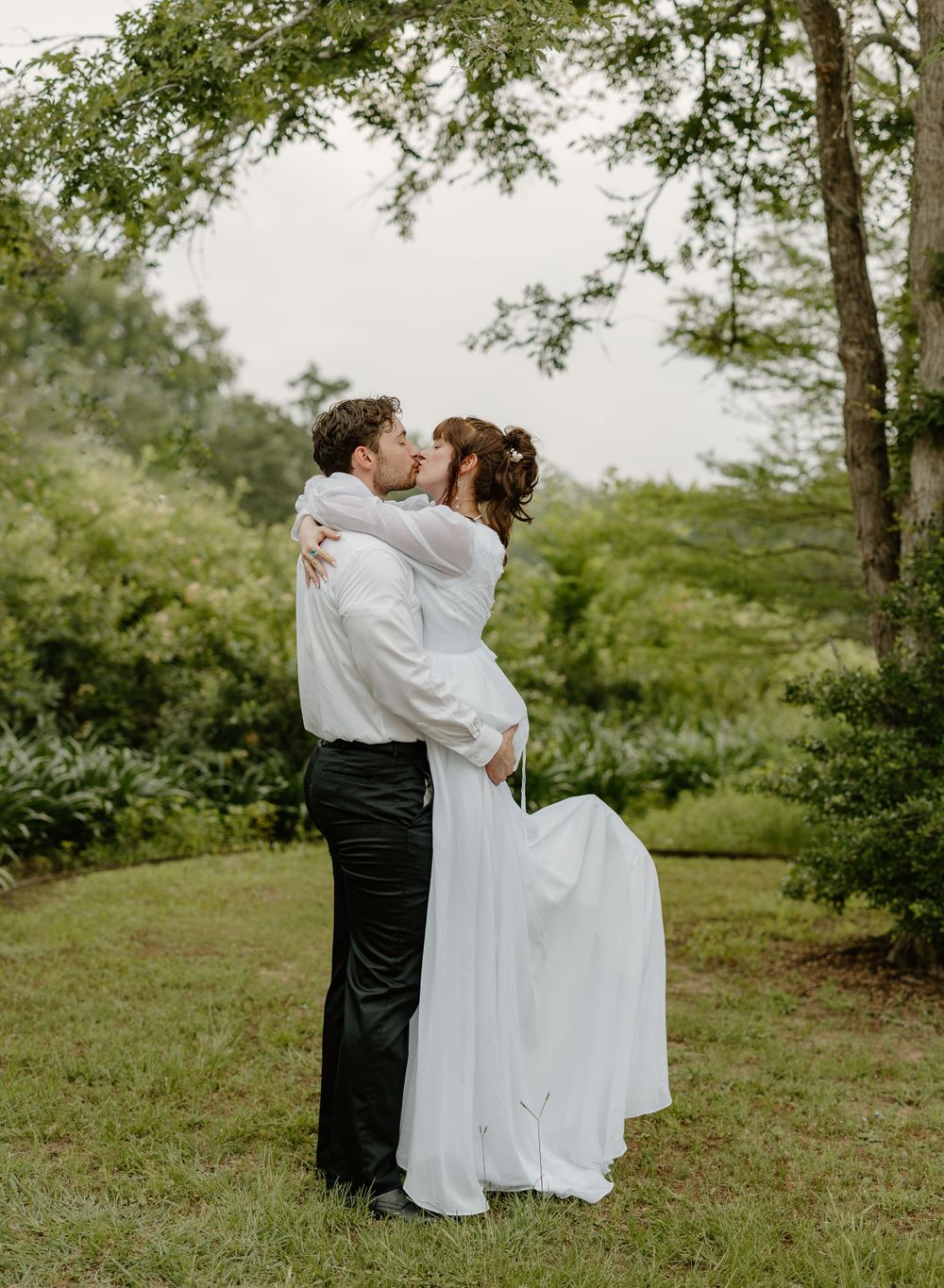 A couple sharing an intimate embrace in a lush garden setting.