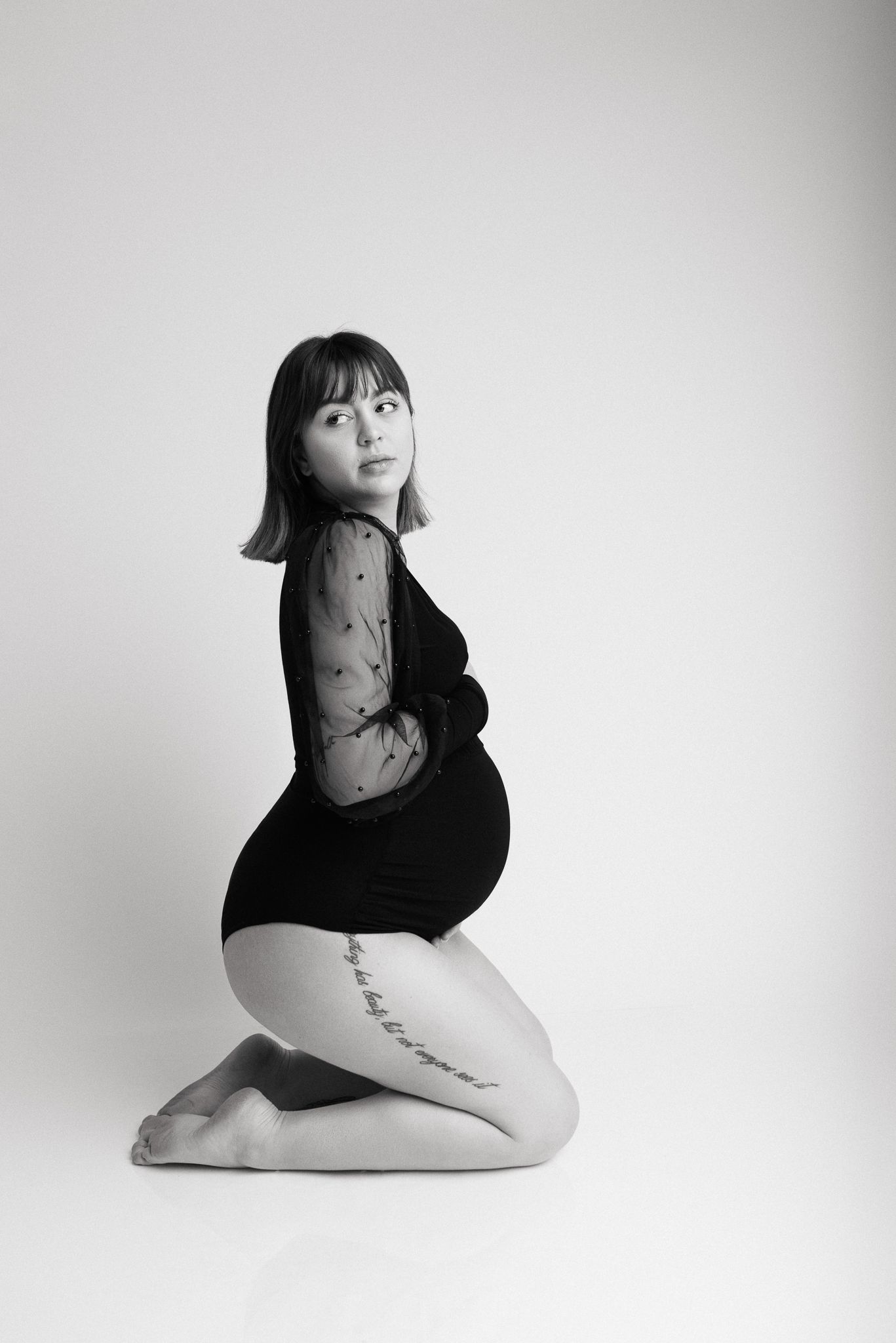 Artistic black and white maternity portrait against light background.