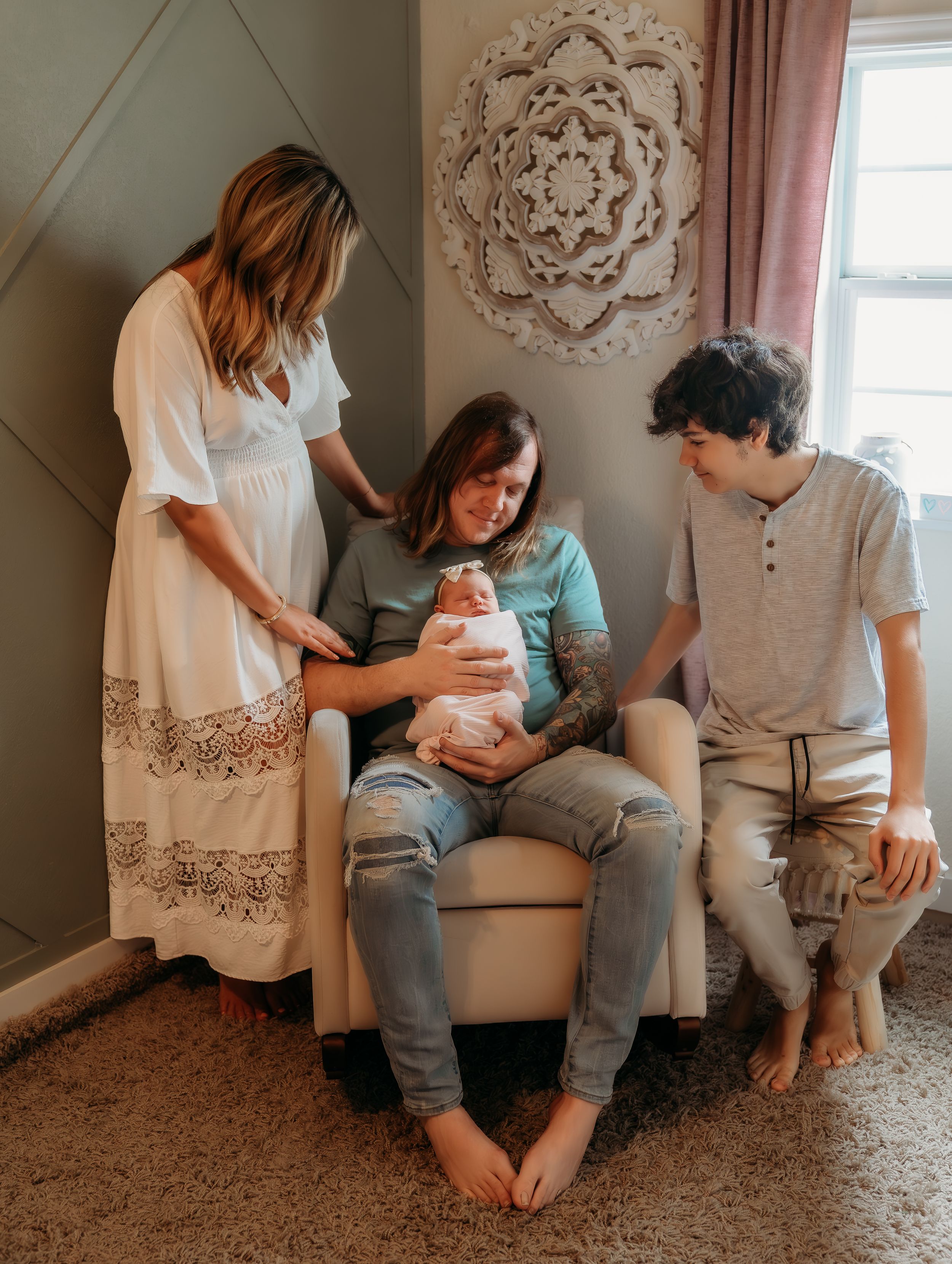 Three people sharing an intimate moment with a newborn baby in a cozy living room with soft decor.