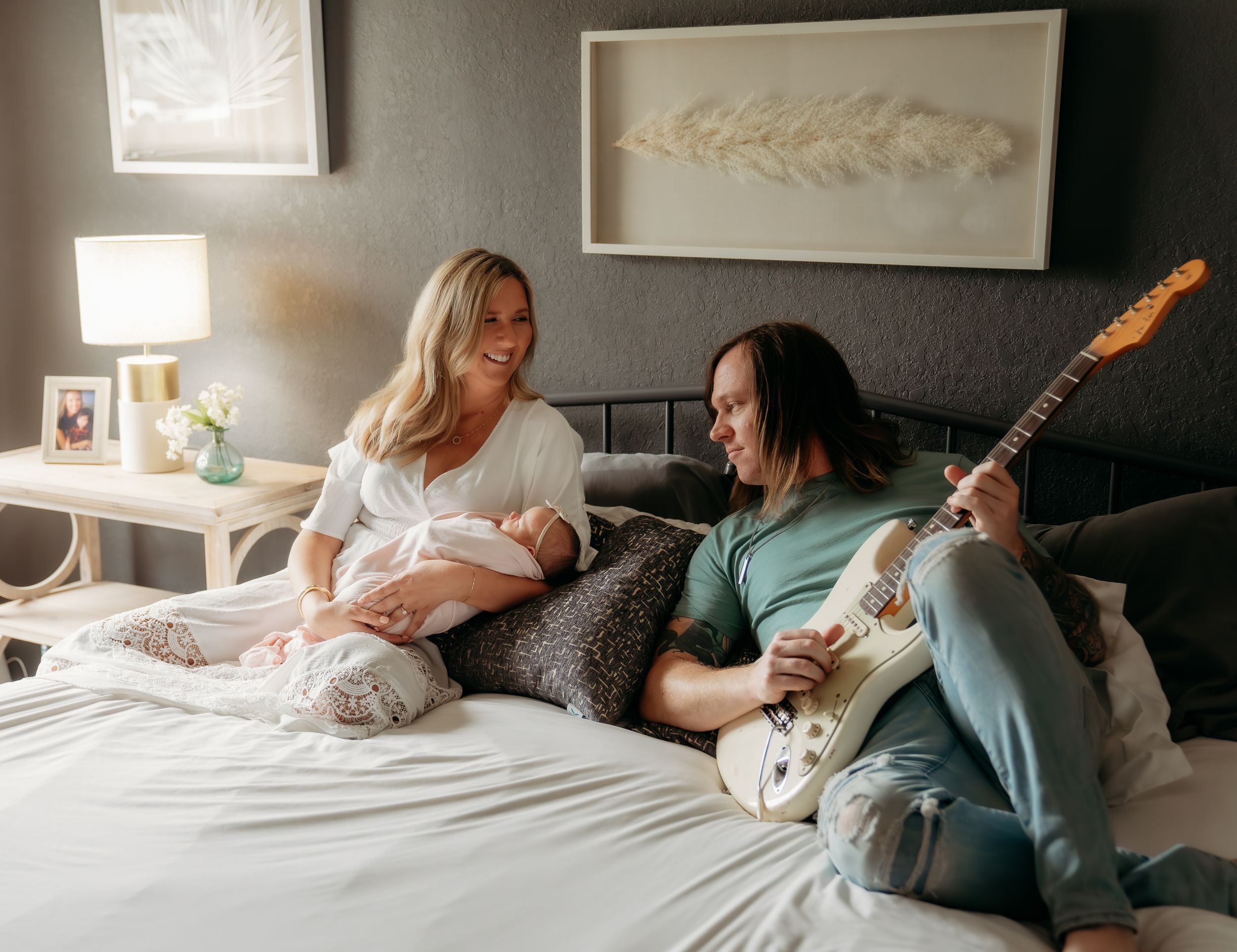 Family moment on bed with guitar player and newborn baby.
