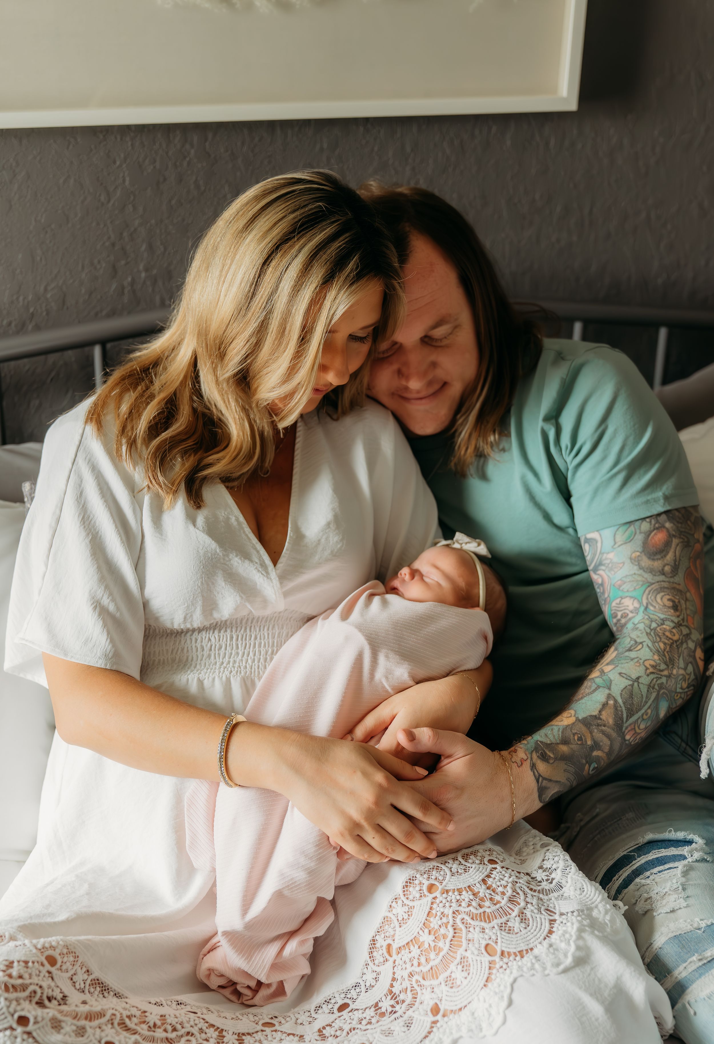 An intimate moment with a newborn baby being cradled by two people in white and mint green clothing.