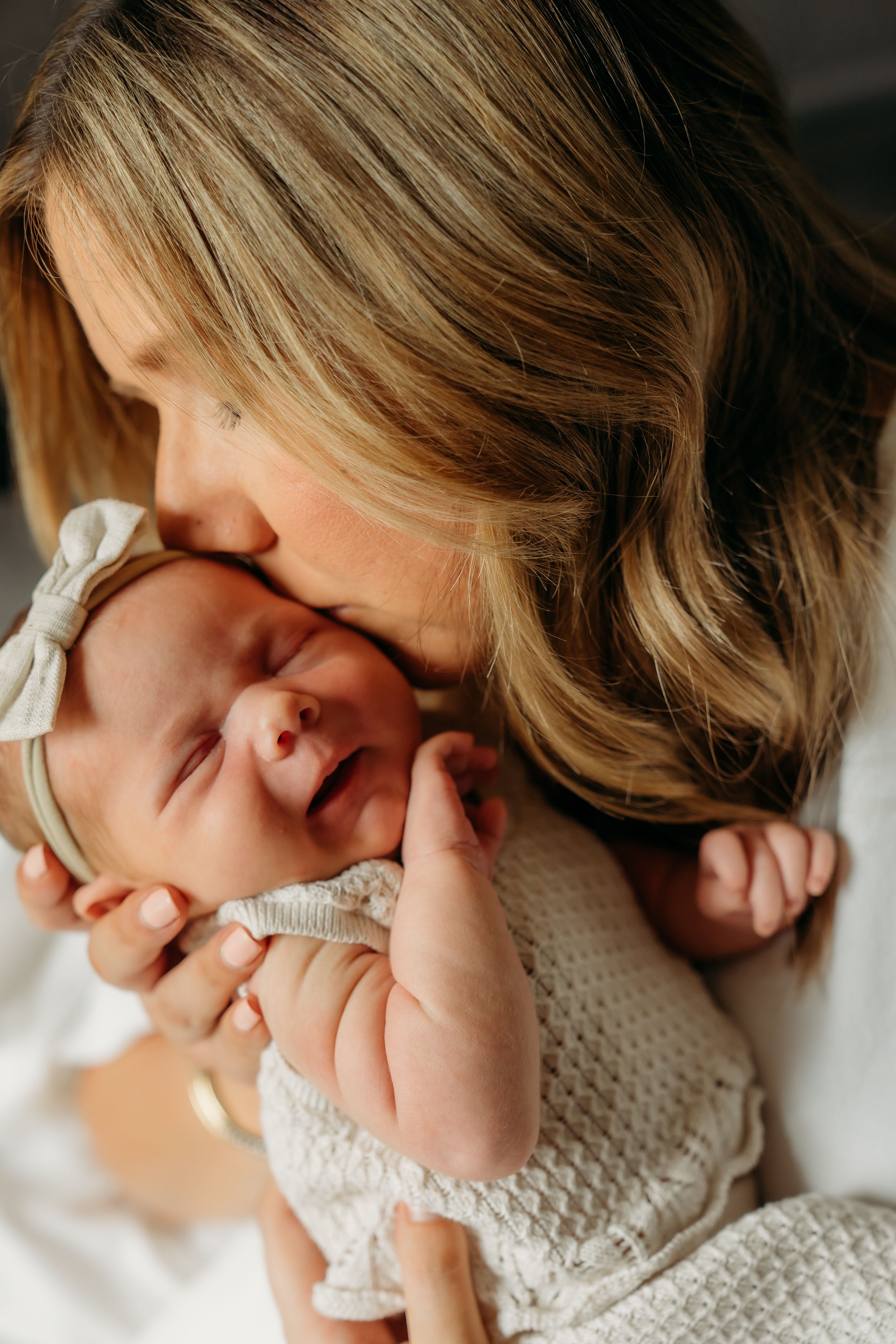 Intimate close-up of parent cradling sleeping newborn in knit outfit.