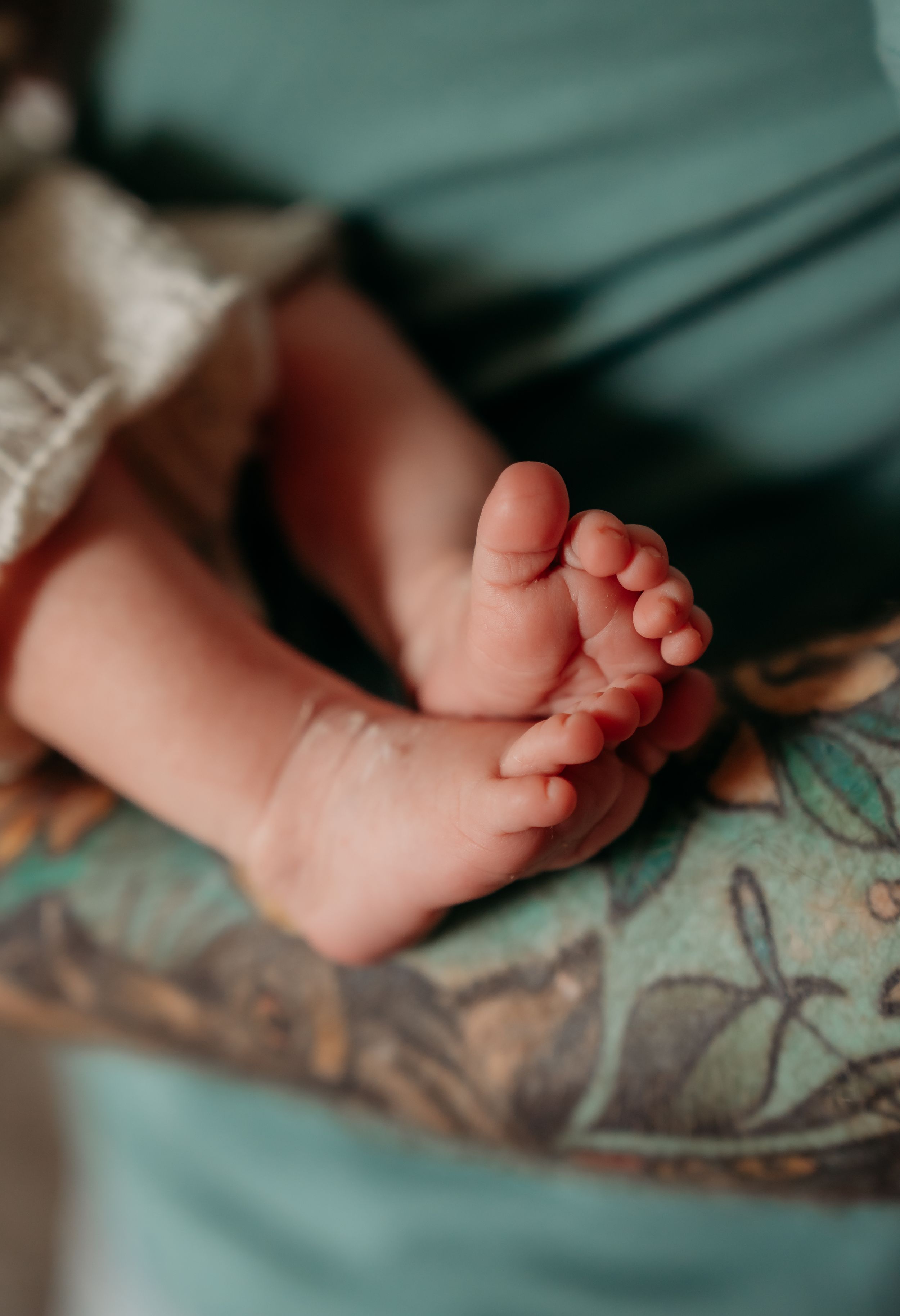 Close-up of baby's tiny feet on floral patterned fabric.
