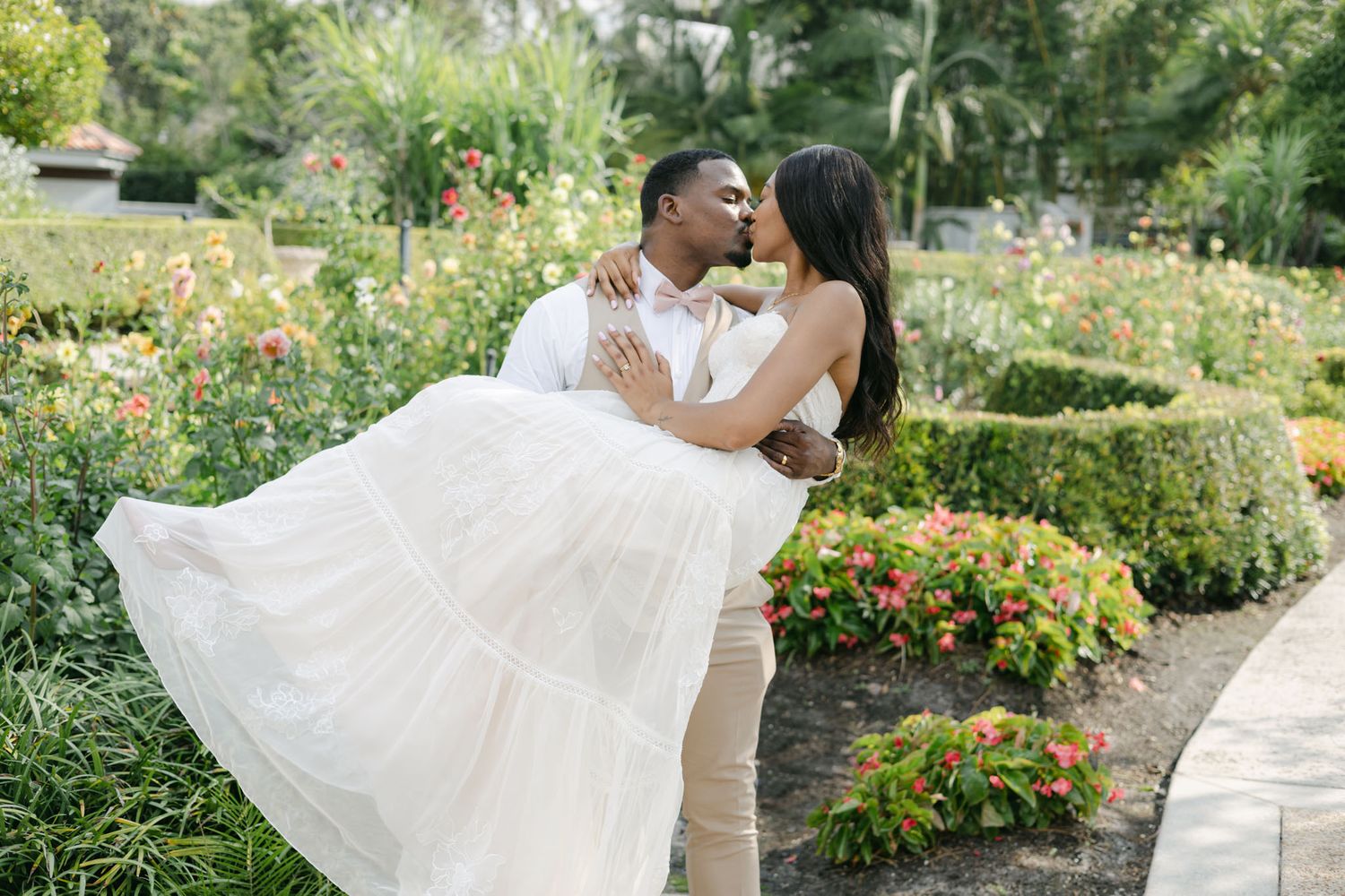 Black bride and groom enjoying champagne in a flower garden in the summer. wedding photographers in Bradenton