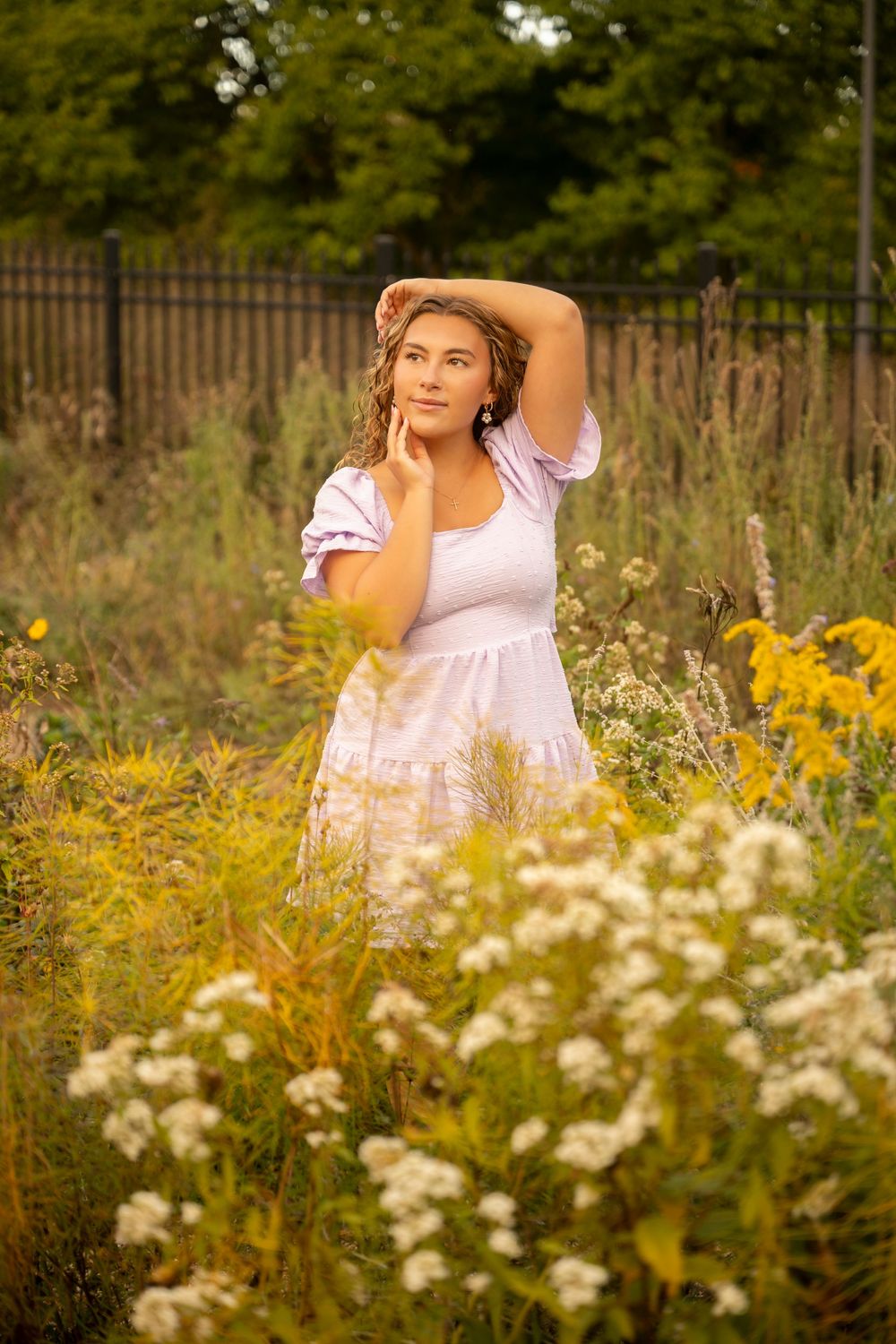 A dreamy summer portrait in a wildflower meadow with golden light, white dress, and blooming yellow and white flowers.