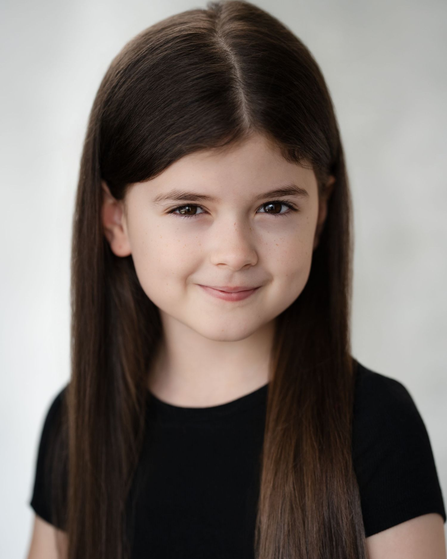 Studio portrait of person with natural curly brown hair wearing black zip-up top in Guildford, Surrey.