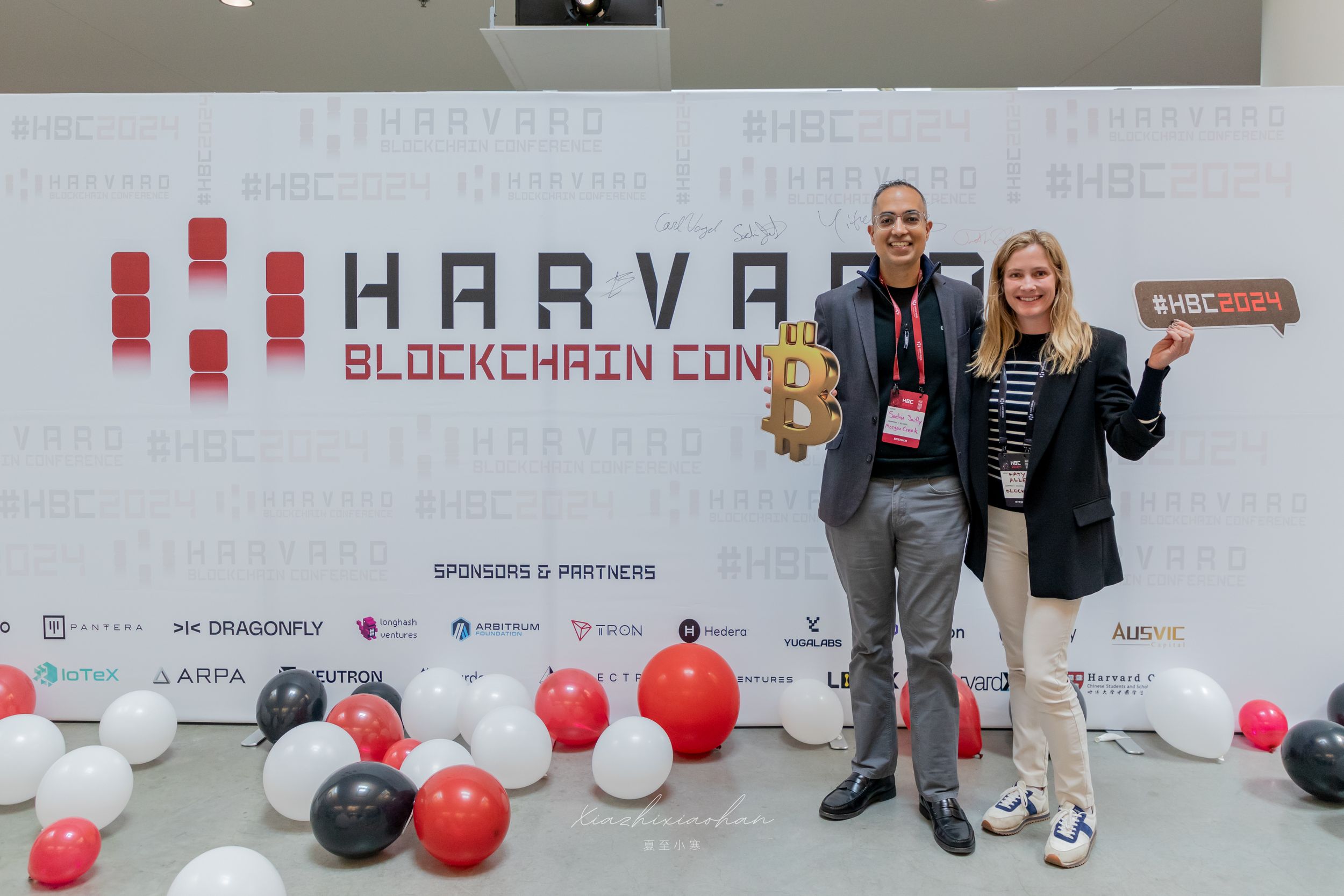 Conference venue with Harvard branding and decorative balloons along the wall.