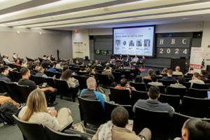 Wide view of lecture hall during professional conference with projected presentation.