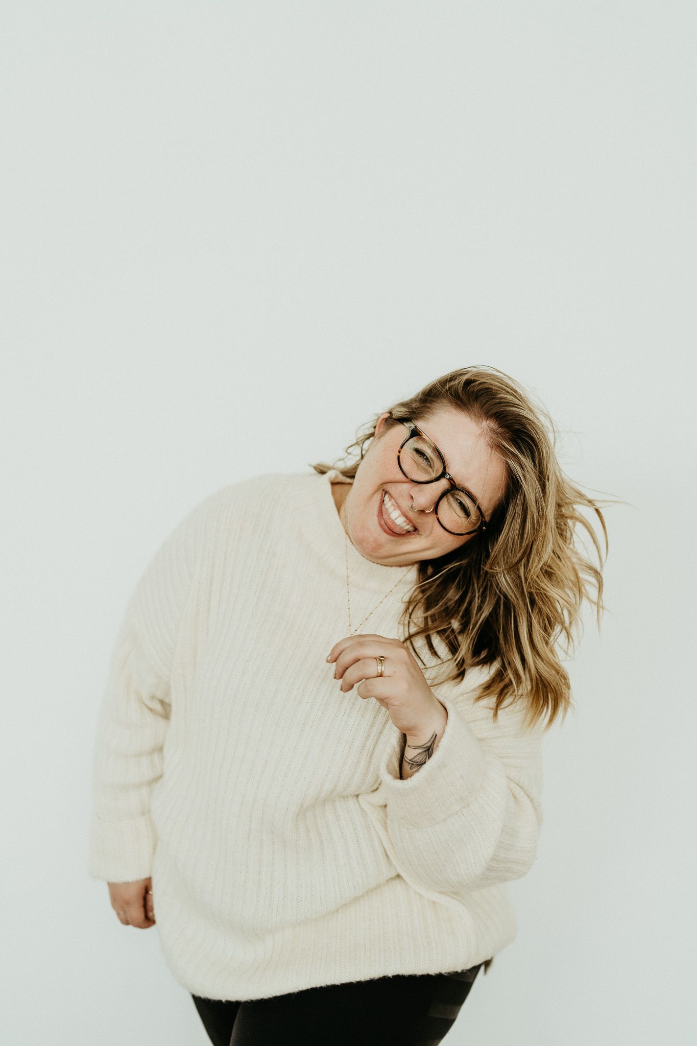 Joyful moment in a cream knit sweater against white background.