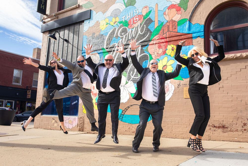 Financial planning team jumping for joy in front of mural wall in Sioux City