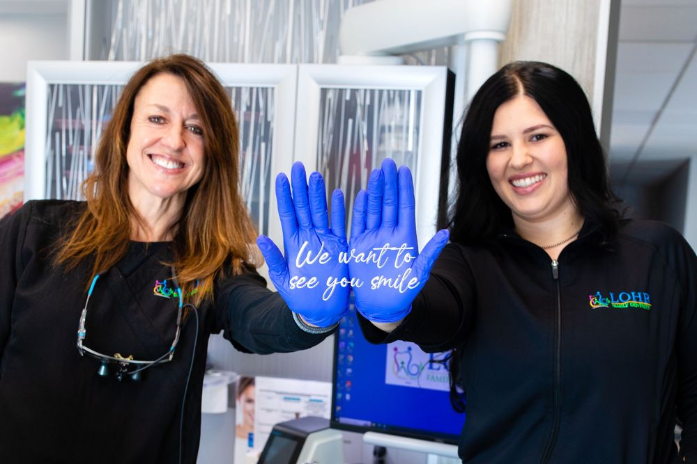 Business branding image of two dental hygienists wearing latex gloves with the words we want to see you smile on the gloves