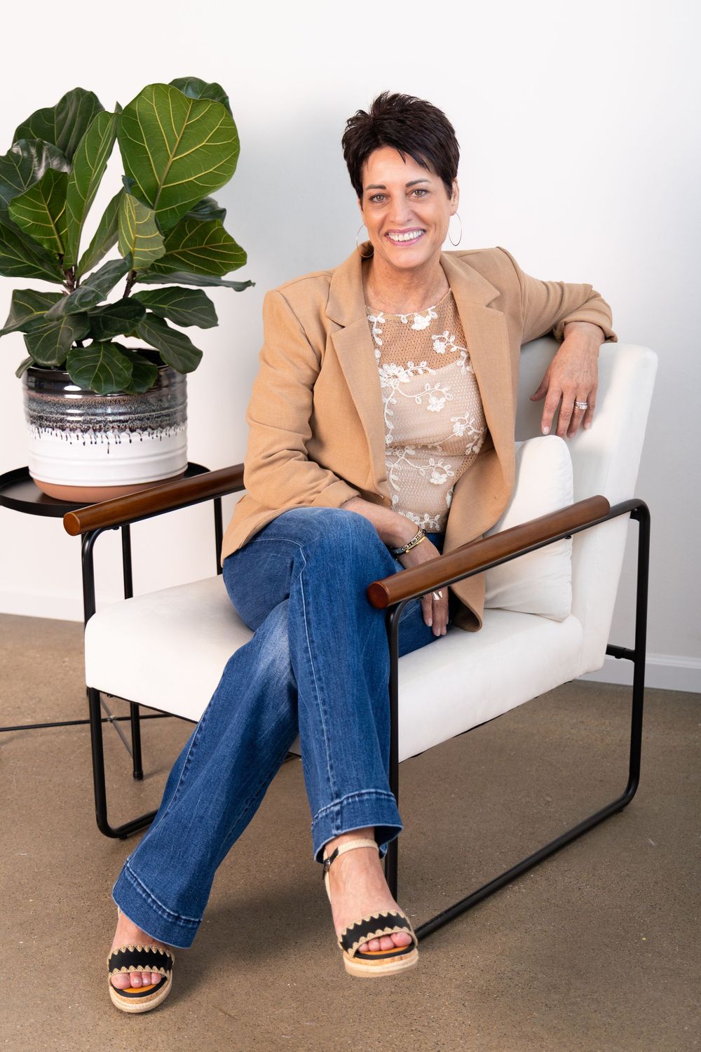 Photo of a life coach sitting on a chair next to a plant