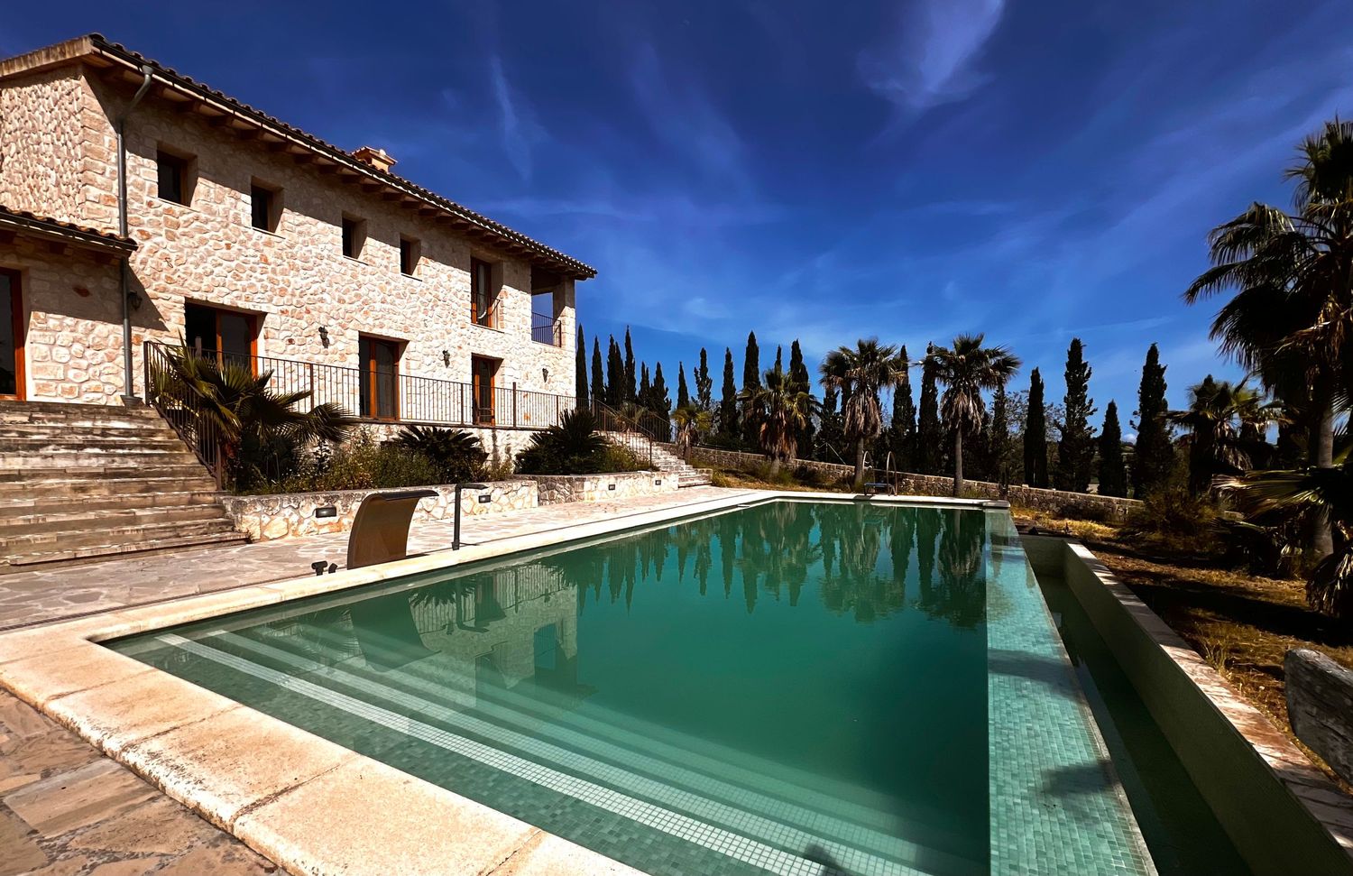 Aerial view of a Mediterranean villa complex with swimming pool and palm-lined driveway.