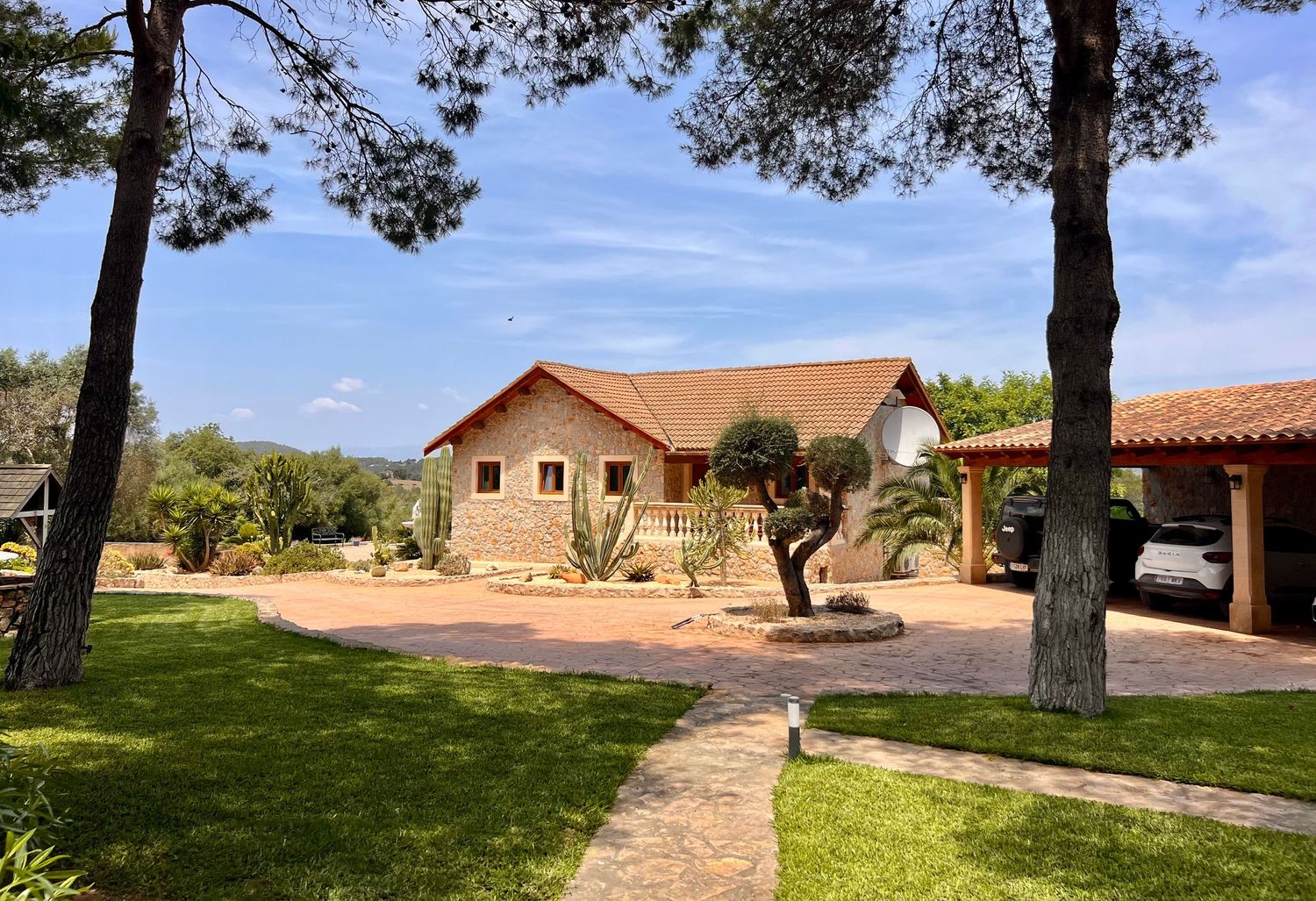 A panoramic view of a desert landscape with houses and trees dotting the terrain under a bright blue sky.