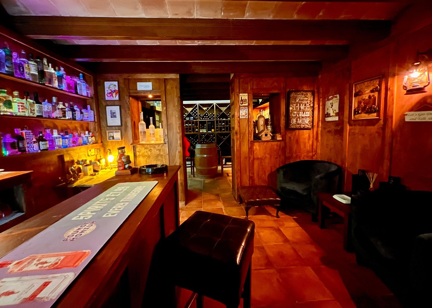 Cozy western-style bar interior with wood paneling, neon signs, and leather seating.