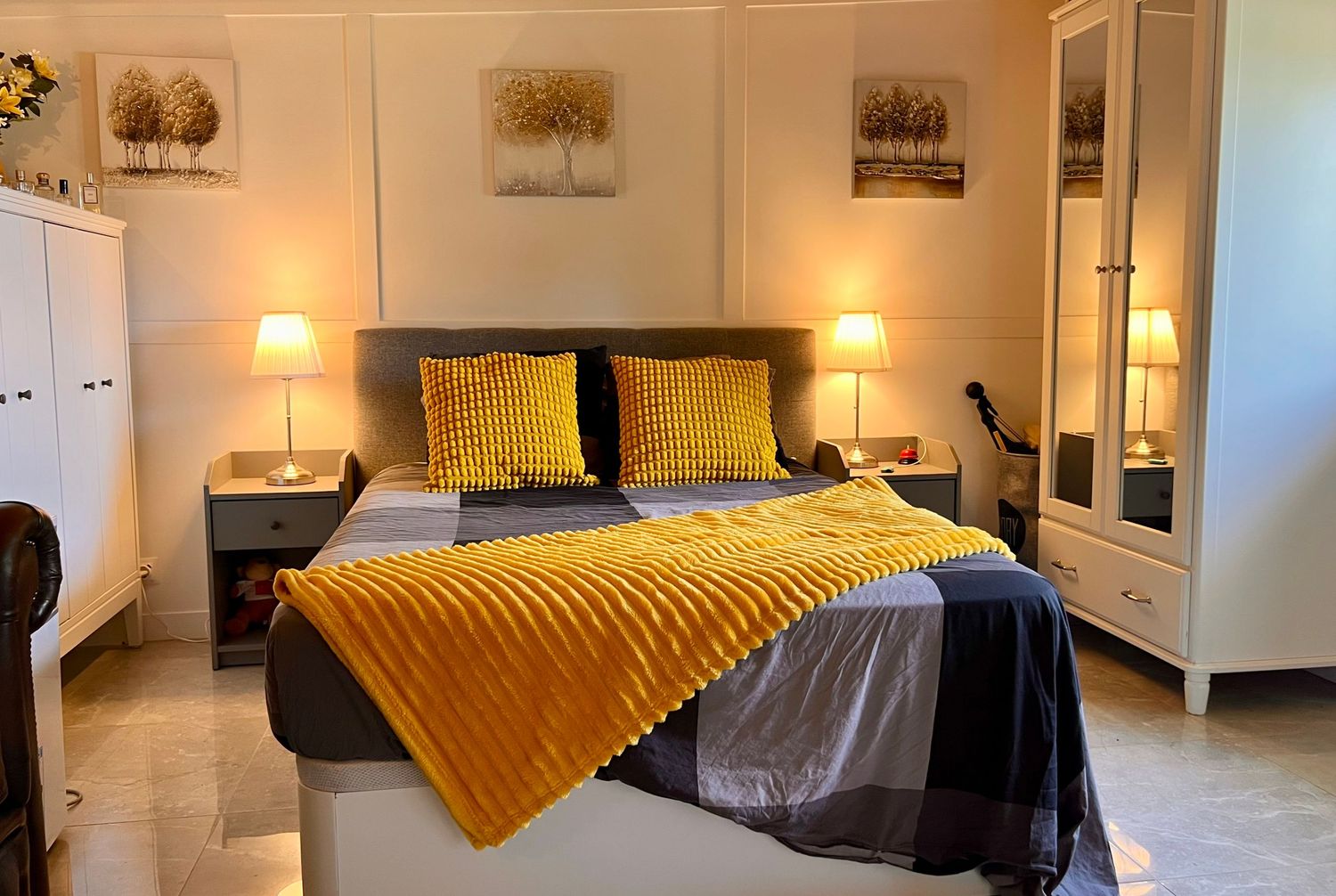 A white and yellow themed bedroom with modern decor features white walls, bedding, and wooden furniture accents.
