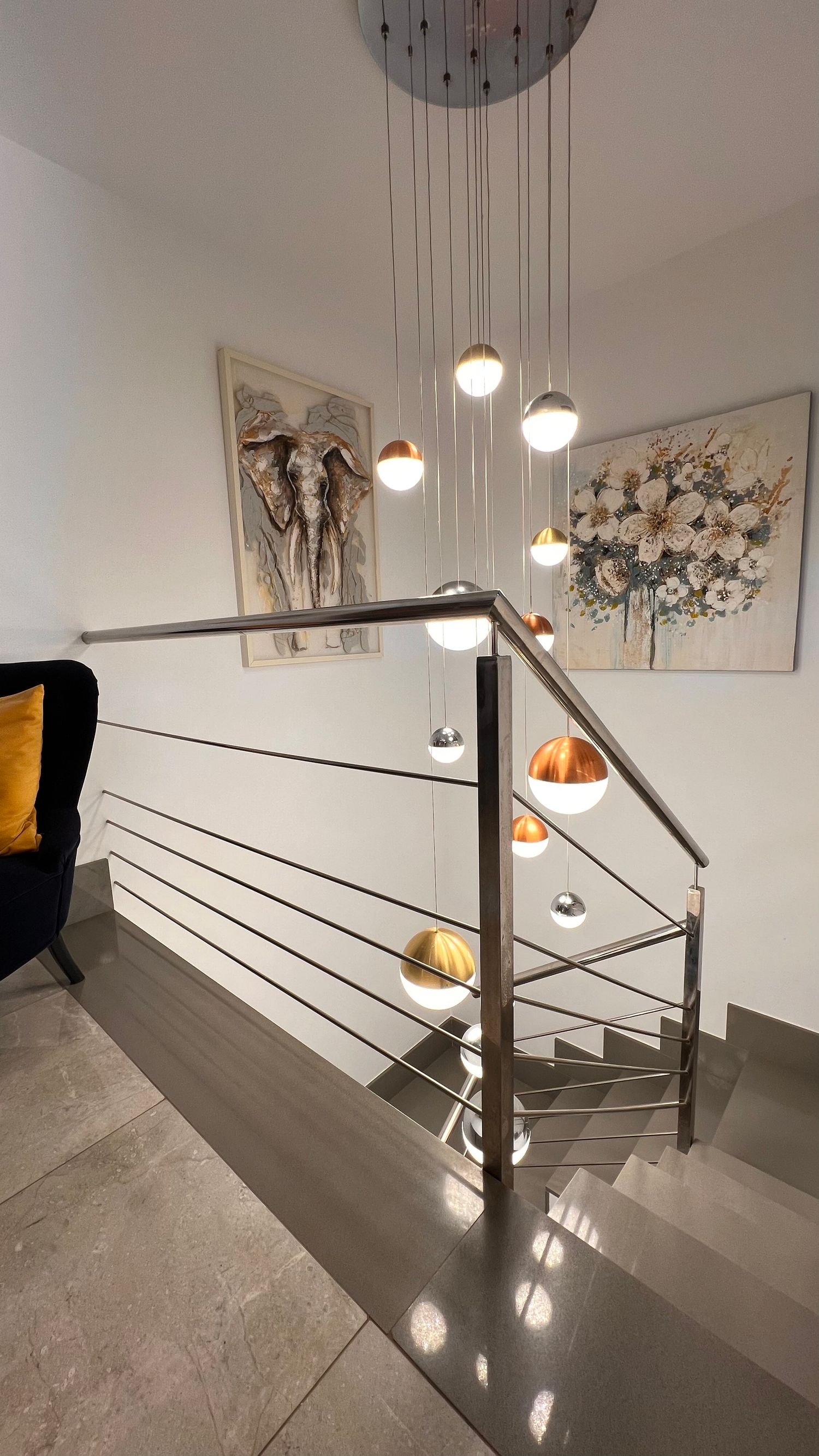 Modern staircase with pendant lights and artistic wall prints in a contemporary home interior.