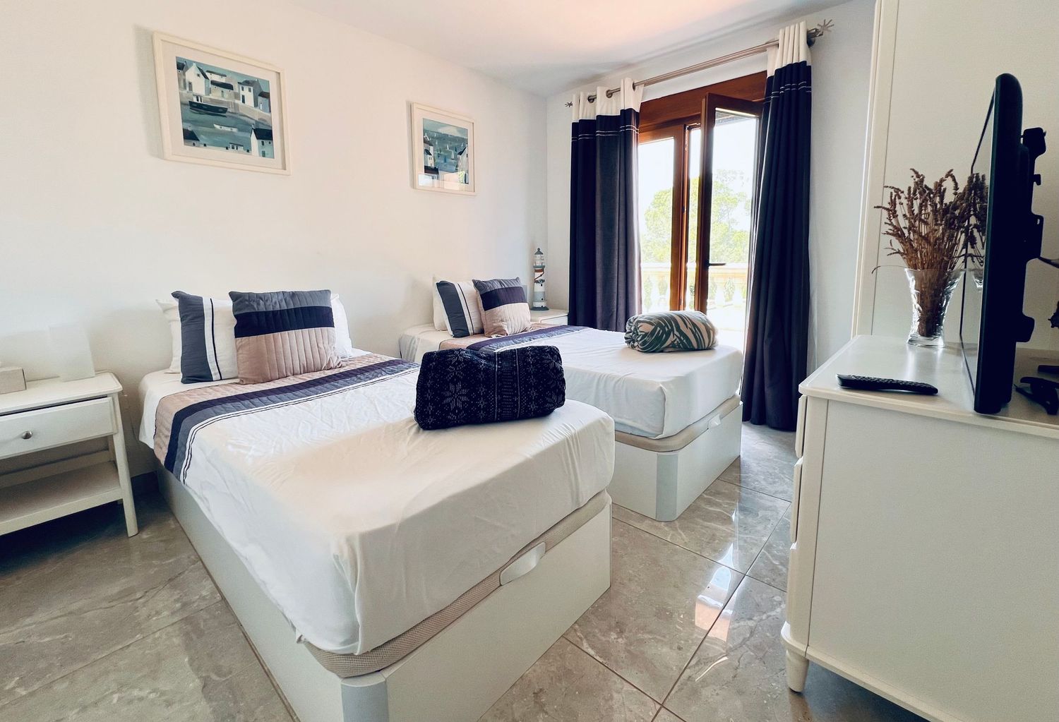 Panoramic view of a bright, modern bedroom with white walls, designer furniture and dark curtains.