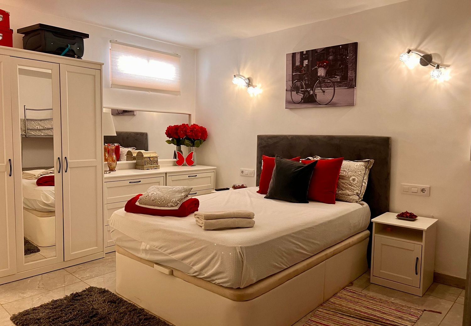 Panoramic view of a contemporary bedroom featuring white furnishings, red accents, and wall-mounted lighting.