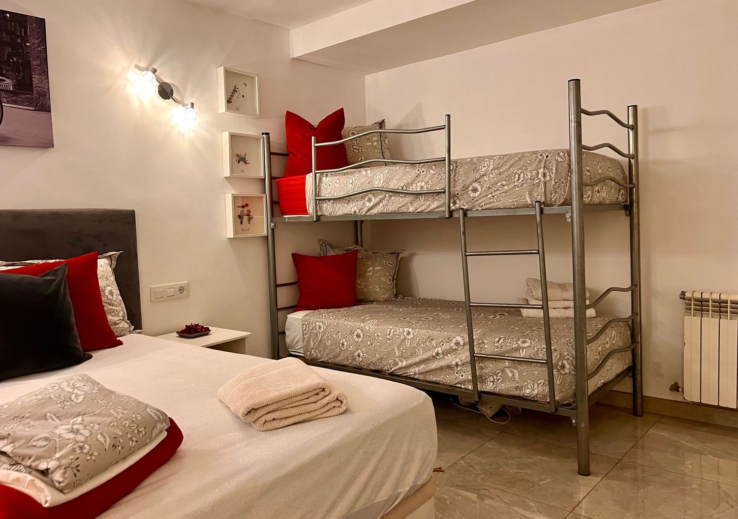 Modern hostel-style bedroom with bunk beds, white linens, and red accent decor against white walls.