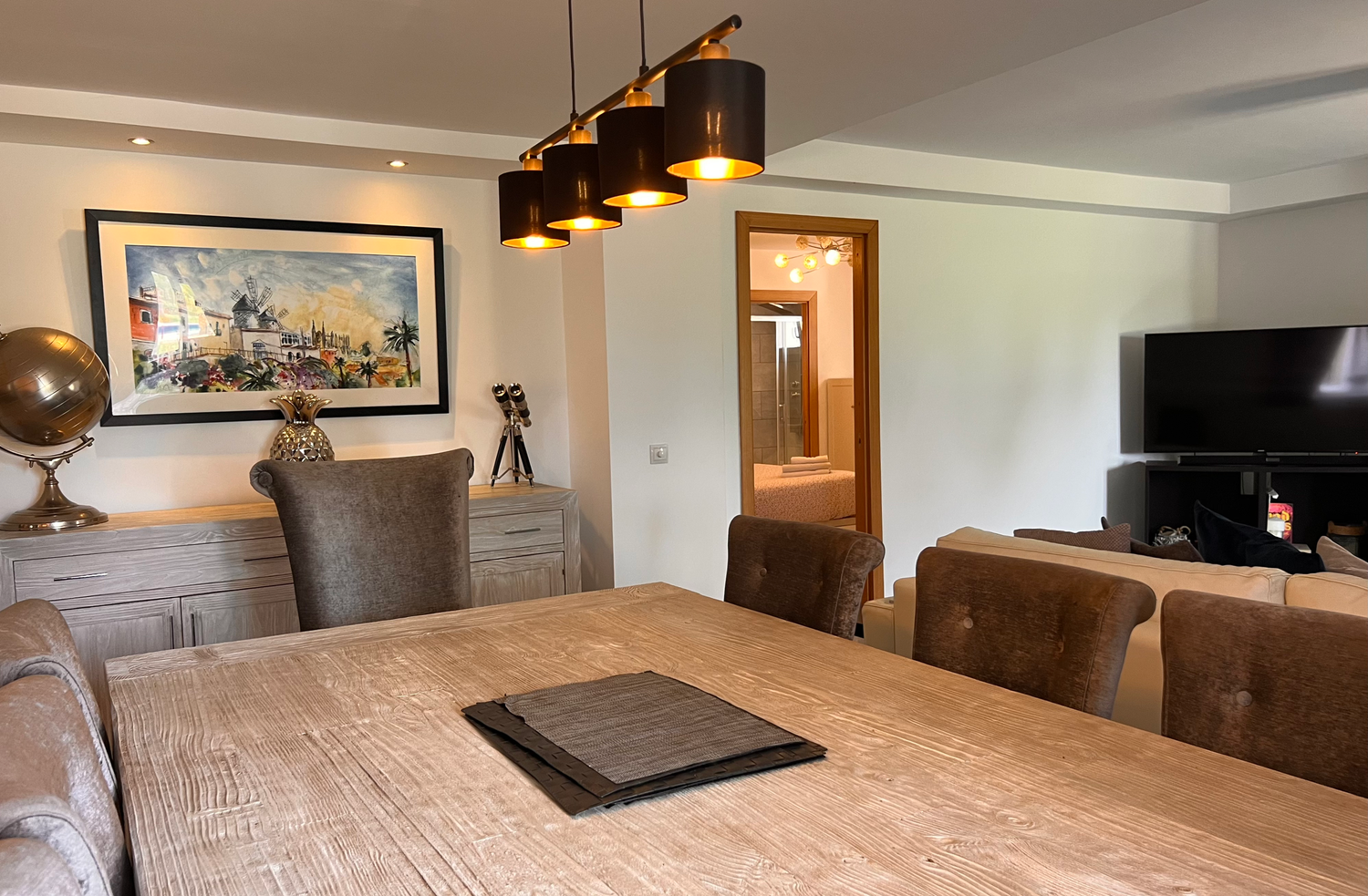 Modern dining room interior with leather chairs, wooden table, art print and decorative telescope mount in corner.