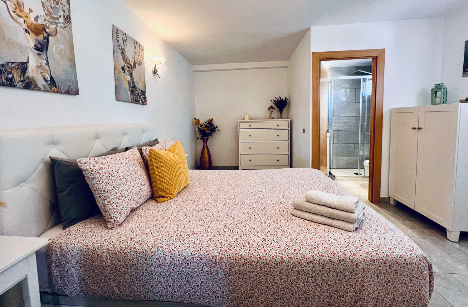 Modern bedroom with pink bedding, yellow accent pillow, and decorative artwork featuring wildlife above the bed.