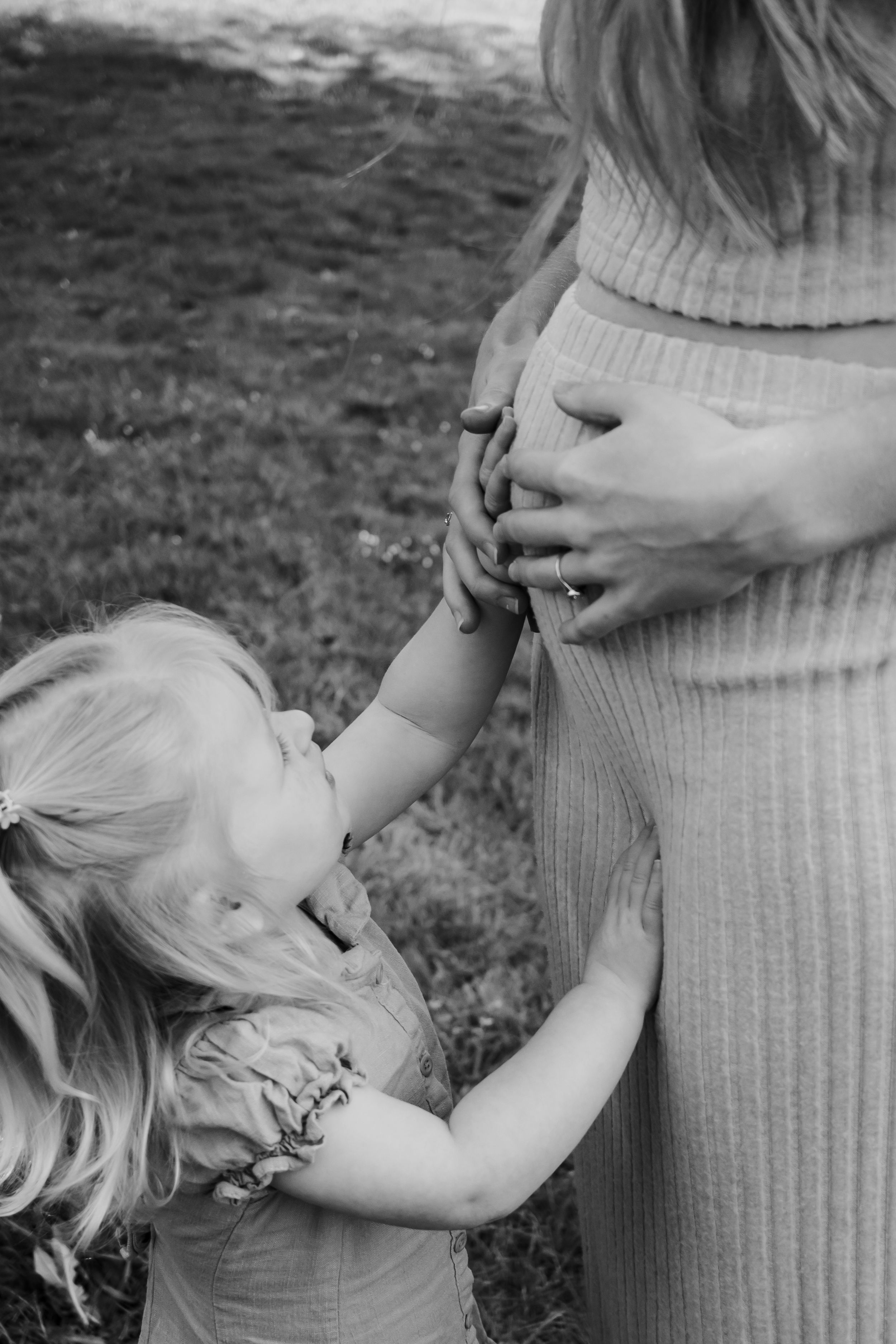 Girl touching her pregnant mum's belly.