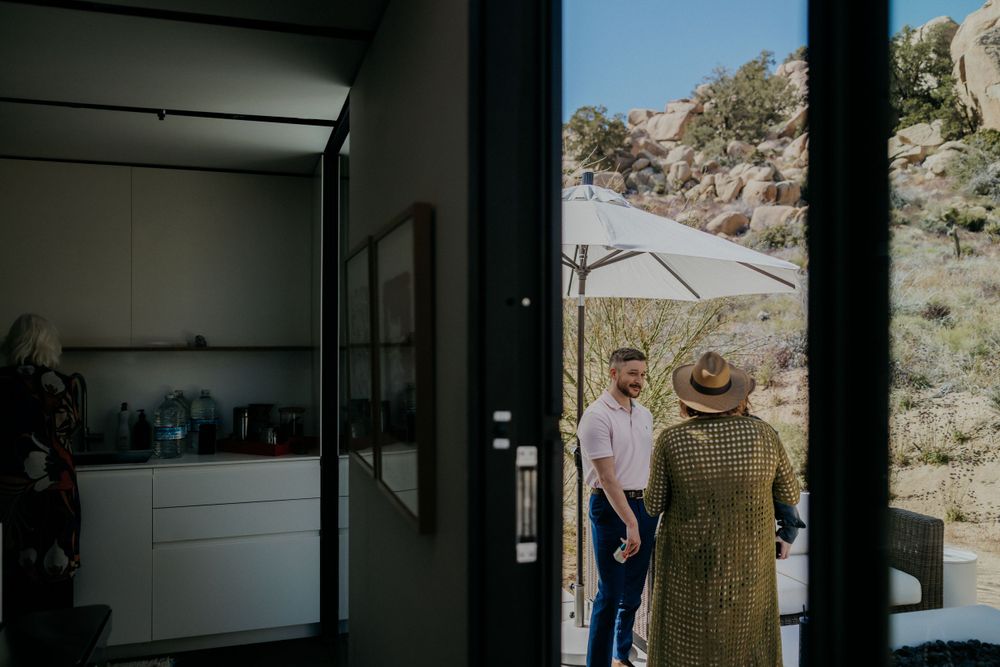 Modern desert home interior with glass doors opening to a rocky landscape and outdoor patio.