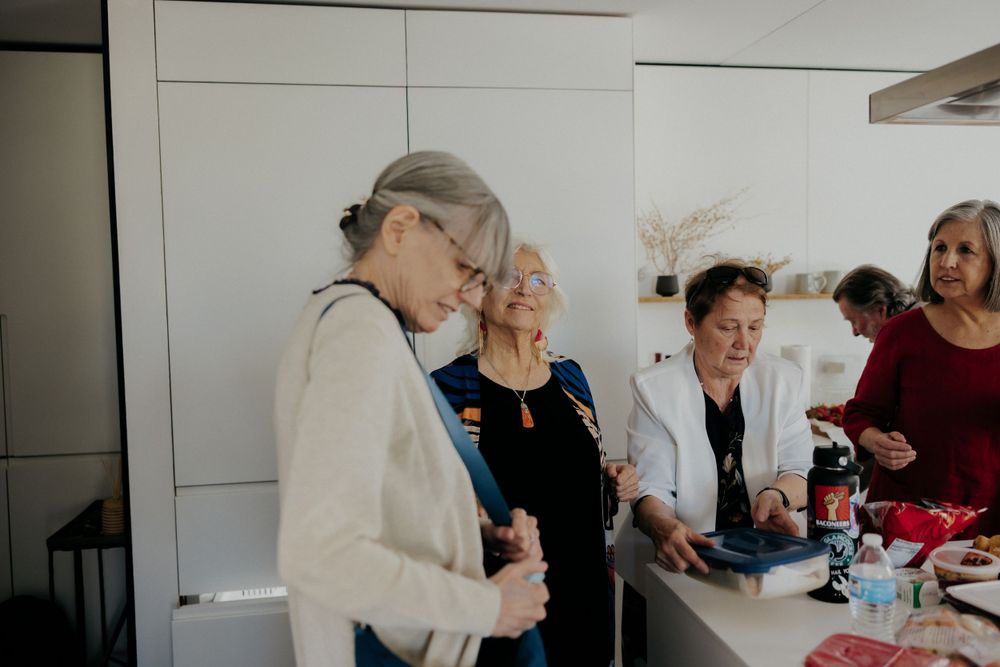 A group of guests gathered in a white kitchen space during a social event.