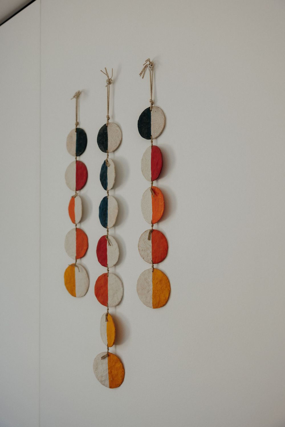 Hanging wall art made of colorful circular geometric shapes in orange and black.