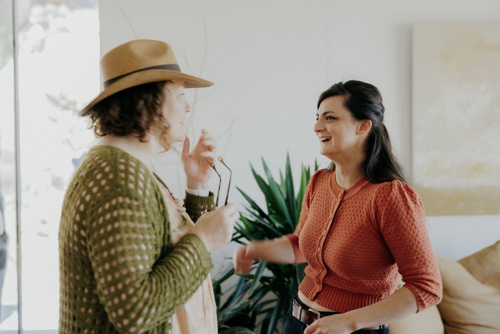 Two people having an animated conversation in a bright interior space with plants.