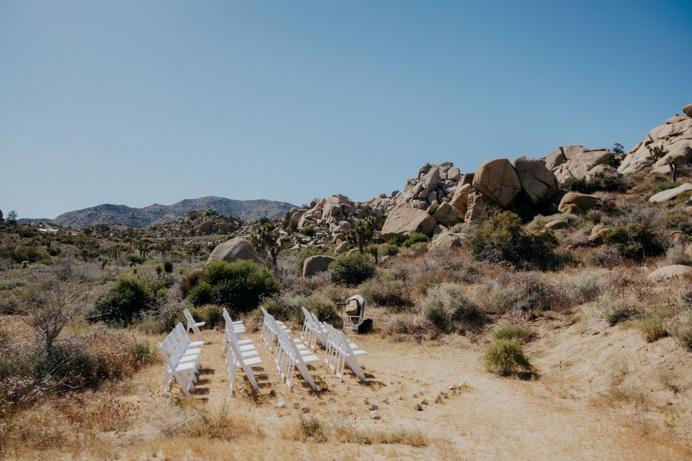Desert hiking path leading through rocky terrain with mountains and Joshua trees in Joshua Tree National Park.