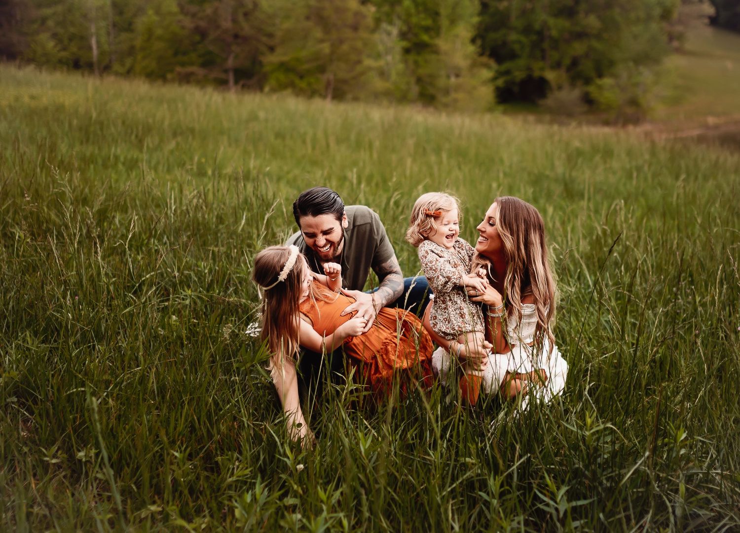 A family sits together in a grassy field on a sunny day sharing joyful moments together.