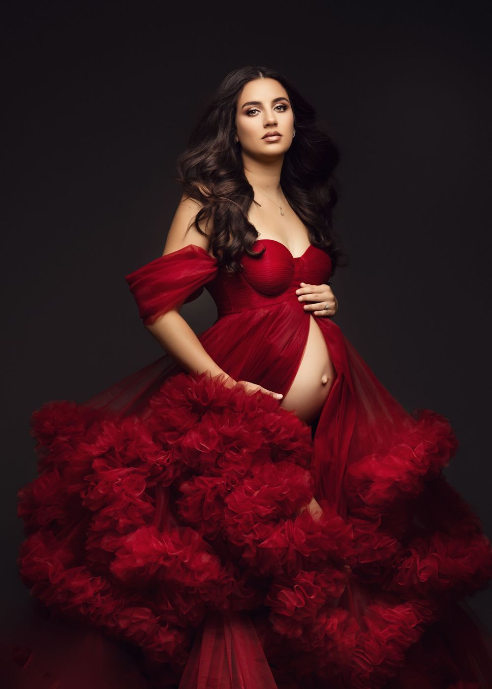 A glamorous burgundy tulle gown with dramatic ruffles is showcased against a dark background in a fashion photo series.