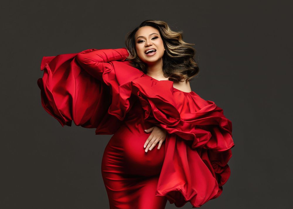 A woman in a flowing red gown twirls elegantly against a dark background, creating dramatic movement and contrast.