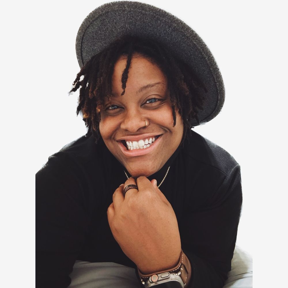 Professional studio portrait showing a joyful smile and black beret against a white background.