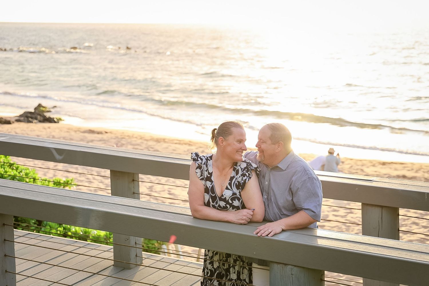 Couple sitting together on wooden bench at beach during golden sunset hour.