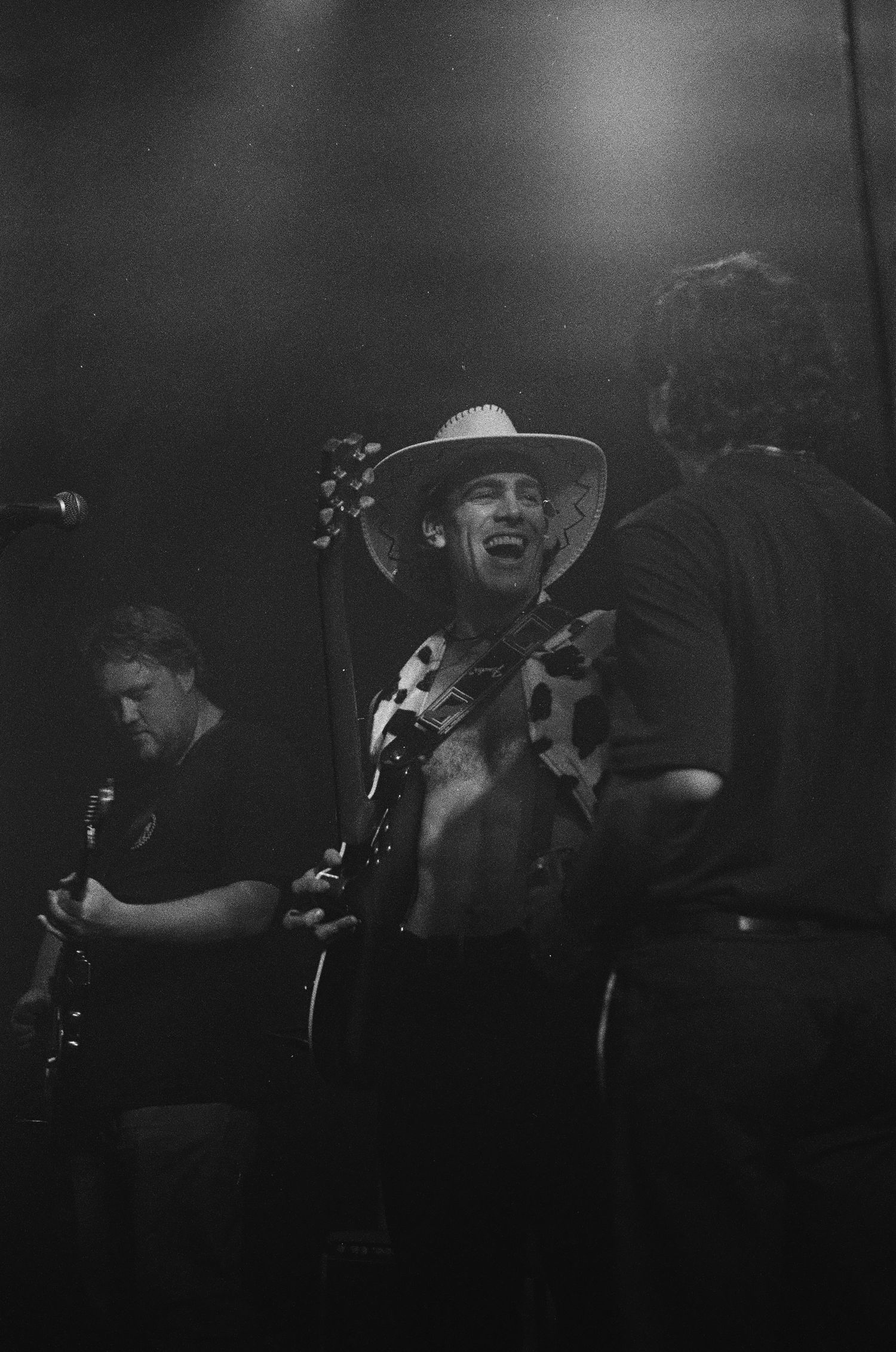 Musicians performing on dark stage with dramatic lighting in black and white.