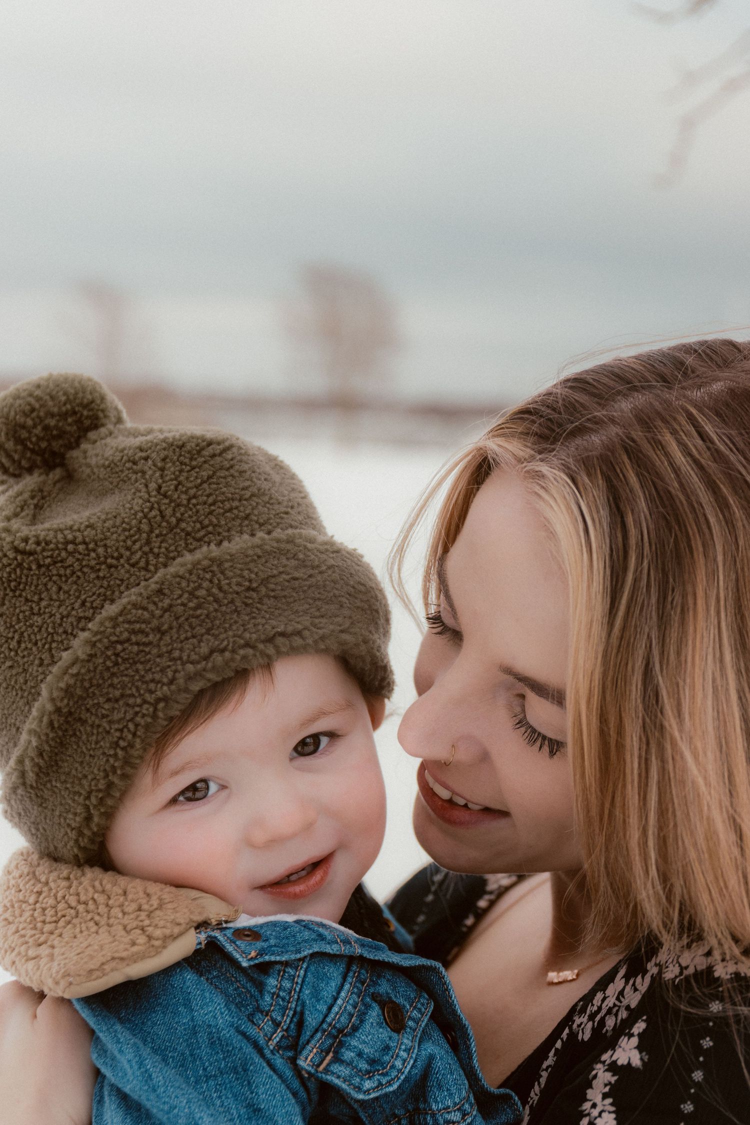 A tender winter moment between parent and child wearing warm clothing outdoors.
