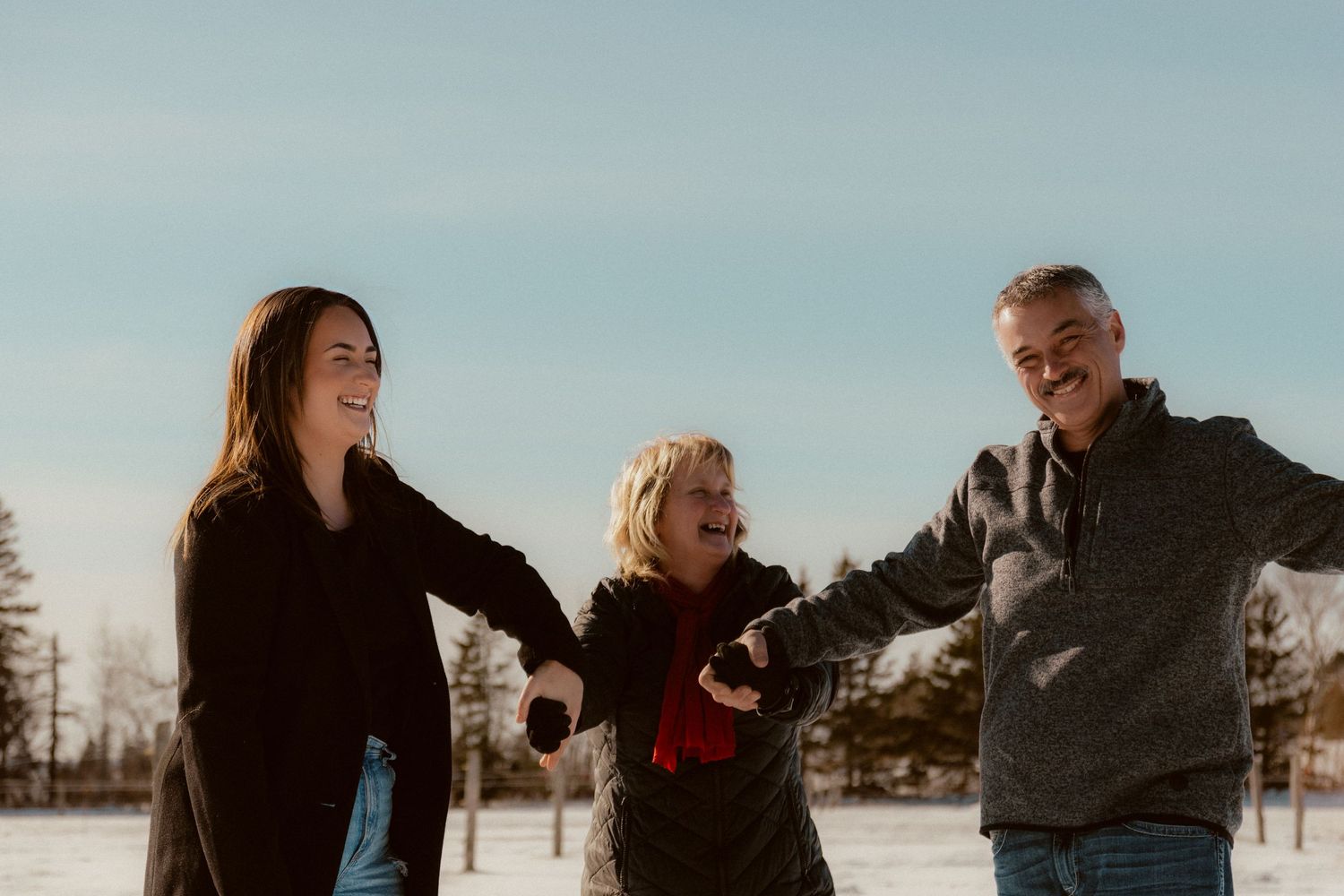 Three people laugh together while enjoying a winter day in the snow.